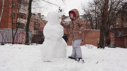 Wall Mural - Father and child playing on winter snowy day. Creating snowman with family on the urban backyard.