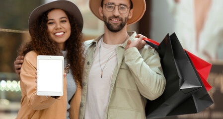 Canvas Print - Couple with tablet computer and shopping bags on city street