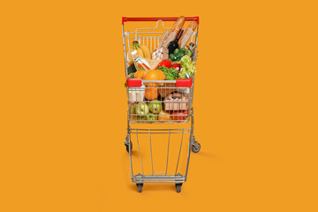 Shopping cart full of groceries on yellow background