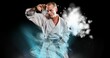 © vectorfusionart - Composition of male martial artist over trails of smoke on black background