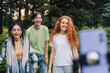 © Strelciuc - A group of people using a tripod and phone laughing while shooting video remotely distance communication on mobile phone. Records a video in nature