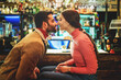 Couple of romantic young people rubbing noses sitting at pub's counter