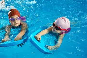 Wall Mural - Two little girls learning to swim in indoor pool with pool board