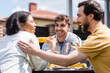 © LIGHTFIELD STUDIOS - Smiling man looking at blurred multiethnic friends with wine near food during picnic outdoors