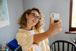 © Drobot Dean - Young beautiful smiling curly woman in glasses taking selfie