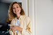 © Drobot Dean - Young beatiful smiling curly woman with phone looking at camera