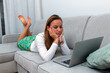 young woman lying on the sofa with laptop computer