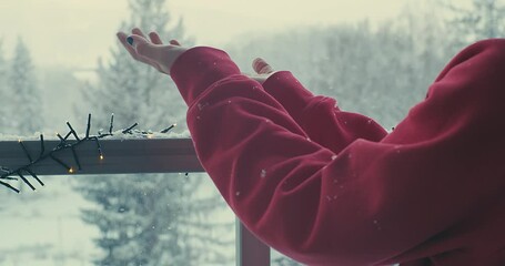 Wall Mural - Woman catching snowflakes. Female relax on terrace at home in winter day. Health care, authenticity, sense of balance and calmness. Fresh air, It's Snow time. 4K Video