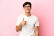 © luismolinero - Young Argentinian man isolated on pink background giving a thumbs up gesture