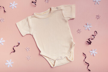 Wall Mural - Yellow baby bodysuit mockup for logo, text or design on pink background with winter decotations top view