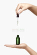 Skincare cosmetic ads. Graceful female hands holding a cosmetic dropper bottle over a white background with copyspace