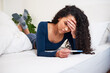 A young multi-ethnic woman lays in bed looking at unwanted pregnancy test result