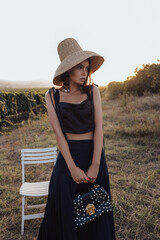 Wall Mural - beautiful woman with dark hair in elegant dress posing in the vineyard on the sunset