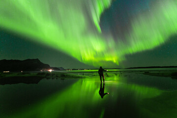massiv aurora reflection on beach with silhouette of a person