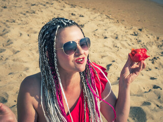 Middle-aged bright woman eating tomato on the beach, detox, healthy food, portrait, c lose up, tasty, smiling enjoy her weekend.Picnic on the beach