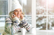 Beautiful elderly woman sits on the background of the window in winter