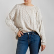 Woman wearing white chunky sweater and blue jeans isolated on white background.