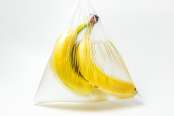 Wall Mural - Bananas in a plastic bag with water on a white background. Creative shot of fruit in water.