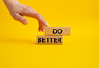 Do better symbol. Wooden blocks with words Do better. Beautiful yellow background. Businessman hand. Business and Do better concept. Copy space.