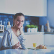© lenets_tan - Young woman with orange juice and tablet in kitchen.
