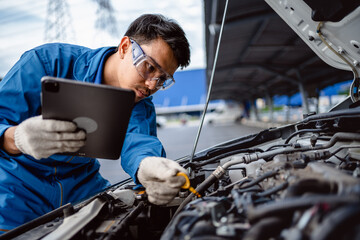 Canvas Print - Automotive mechanic repairman using tablet and pulling dipstick to checking engine oil level engine in the engine room, check the mileage of the car, oil change, auto maintenance service concept.