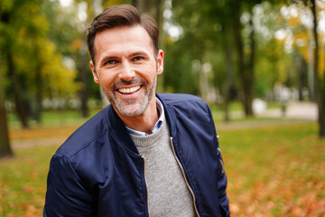 Portrait of happy handsome man  smiling to the camera during outdoor autumn walk.