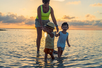 Grandma playing with her two grandsons at the beach in the water