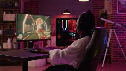 Wall Mural - Over shoulder view of woman streaming first person shooter doing victory hand gesture after win in tournament. African american gamer girl surprised after winning online competition on gaming pc.