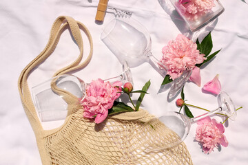 Canvas Print - Flat lay composition with beautiful peonies and wineglasses on white fabric