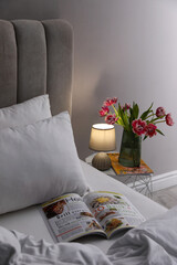 Canvas Print - Stylish lamp, flowers and magazine on bedside table indoors. Bedroom interior elements