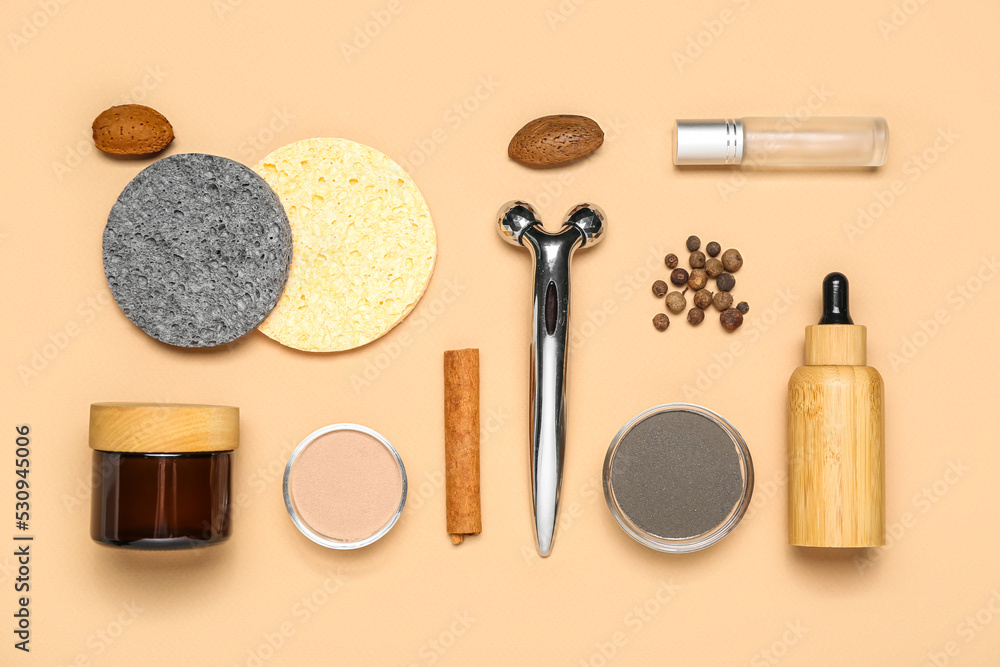 Facial massage tool with cosmetic products and natural components on beige background