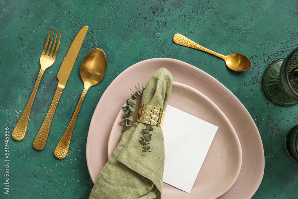 Table setting with blank card and eucalyptus branch on green background