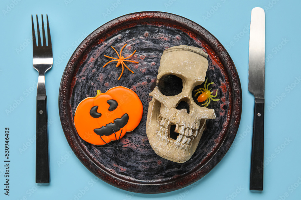 Table setting with scull and Halloween decor on blue background