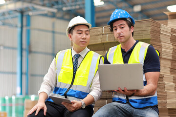 Architect or engineering men and worker standing and checking large warehouse with tablet. Multiethnic two business manager controlling work at warehouse industry building.