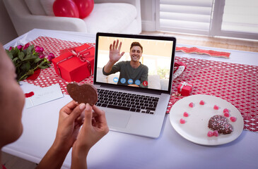 Poster - Diverse couple making valentines date video call the woman holding heart and man waving on laptop sc