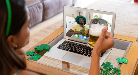 Poster - Caucasian woman holding beer having st patrick's day video call with happy couple on laptop at home