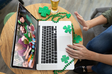 Wall Mural - Caucasian woman at bar making st patrick's day video call waving to friends on laptop