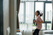 Young Asian woman in sportswear workout exercise by playing video games equipment accessory with sport game on screen in living room at home. Home fitness for good shape and health care concept.