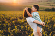 © Strelciuc - Happy boy kissing his mother on the forehead standing in their cornfield at sunset. They are watching their crops. Happy childhood. Mother's love. Love between