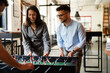 © JustLife - Colleagues having fun at work. Businessman and businesswoman playing table soccer..