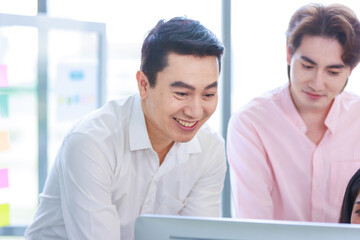 Wall Mural - Millennial Asian beautiful successful professional businesswoman sitting smiling pointing finger showing data information on computer monitor to male businessmen female colleague in company office