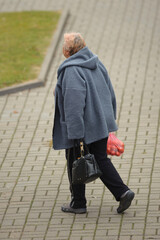 Wall Mural - an old woman walks down the street with a bag of tomatoes