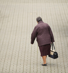 Wall Mural - old woman walking down the street with a bag