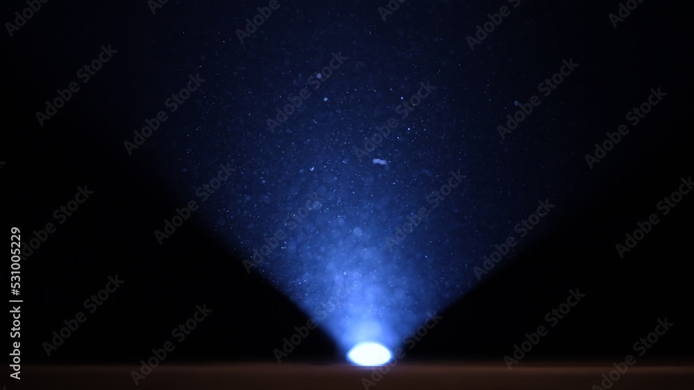 Flashlight Particles Small particles of dust illuminated by a blue beam of light on a black ...