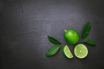 Green lime with sliced and green leaf on black dark background , top view , flat lay.