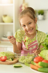 Wall Mural - Beautiful girl preparing a salad in the kitchen