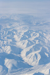 Wall Mural - Aerial view of snow-capped mountains. Winter snowy mountain landscape. Kolymsky ridge (Gydan ridge), Kolyma Mountains, Magadan Region, Siberia, Russian Far East. Travel to the far north of Russia.