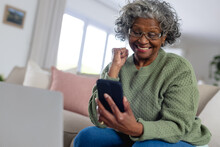 Happy Senior African American Women In The Sunny Living Room Using Smartphone