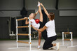 © master1305 - Sport training with coach. Preparing for sport competition. Beginner gymnastics athletes doing exercises with gymnastics equipment at sports gym, indoors.