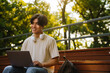 Young handsome smiling asian boy with laptop looking aside